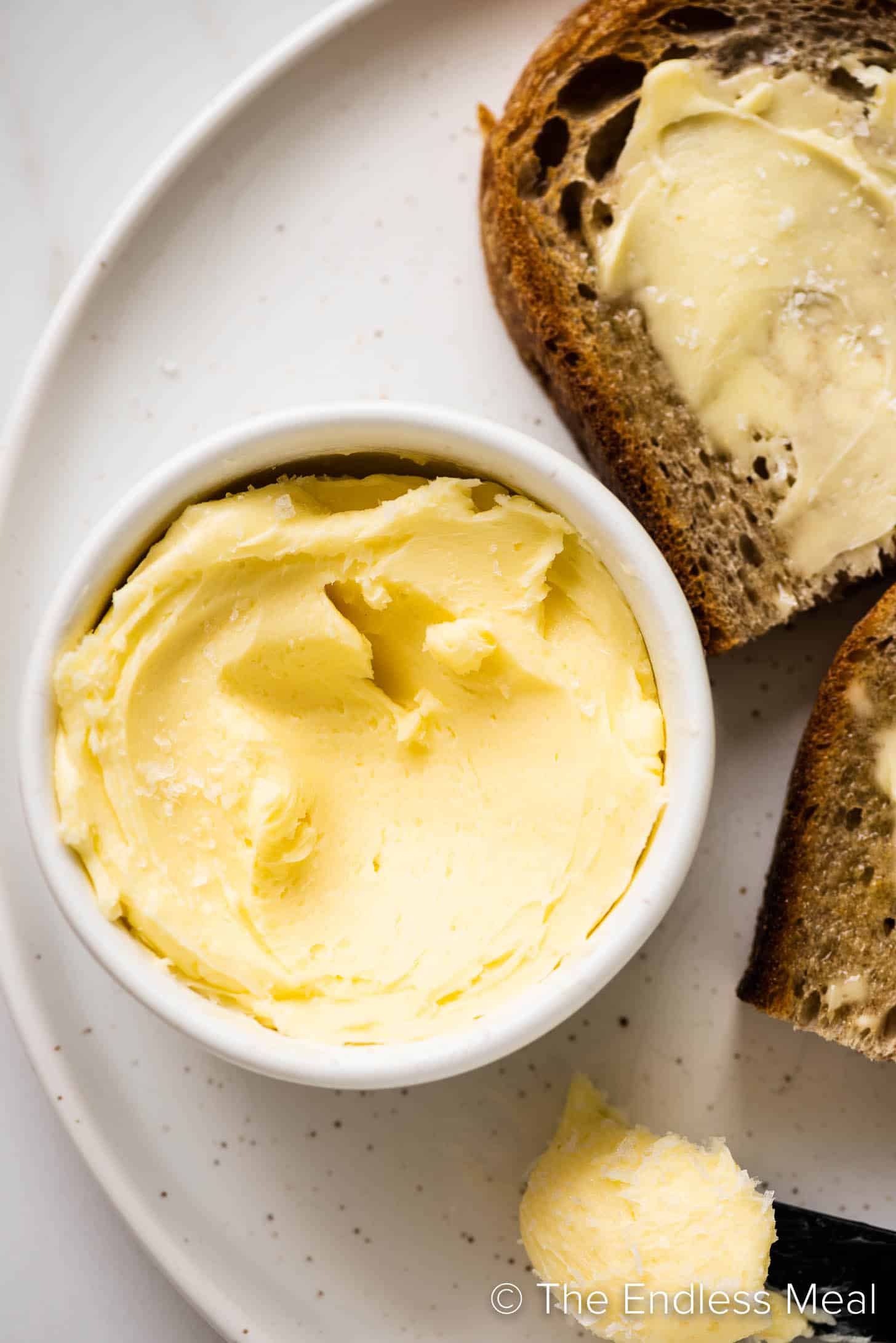 a close up of Homemade Butter next to a plate of buttered toast