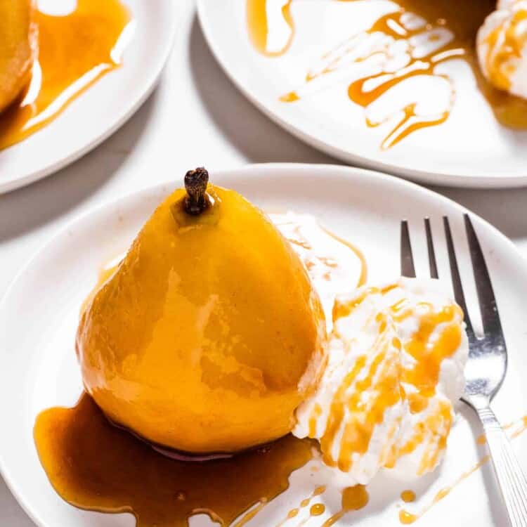 An Amaretto Poached Pear on a plate drizzled in amaretto glaze.