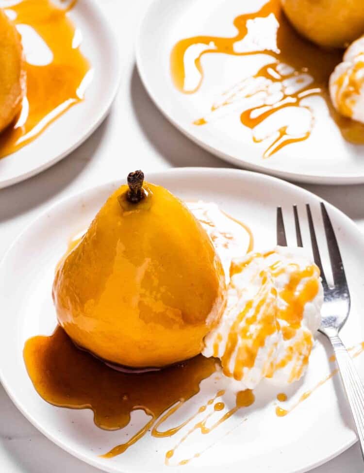 An Amaretto Poached Pear on a plate drizzled in amaretto glaze.