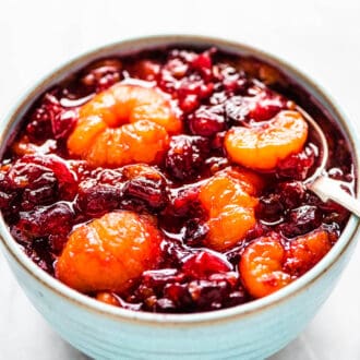 Cranberry sauce with whole mini mandarin oranges in a blue bowl.