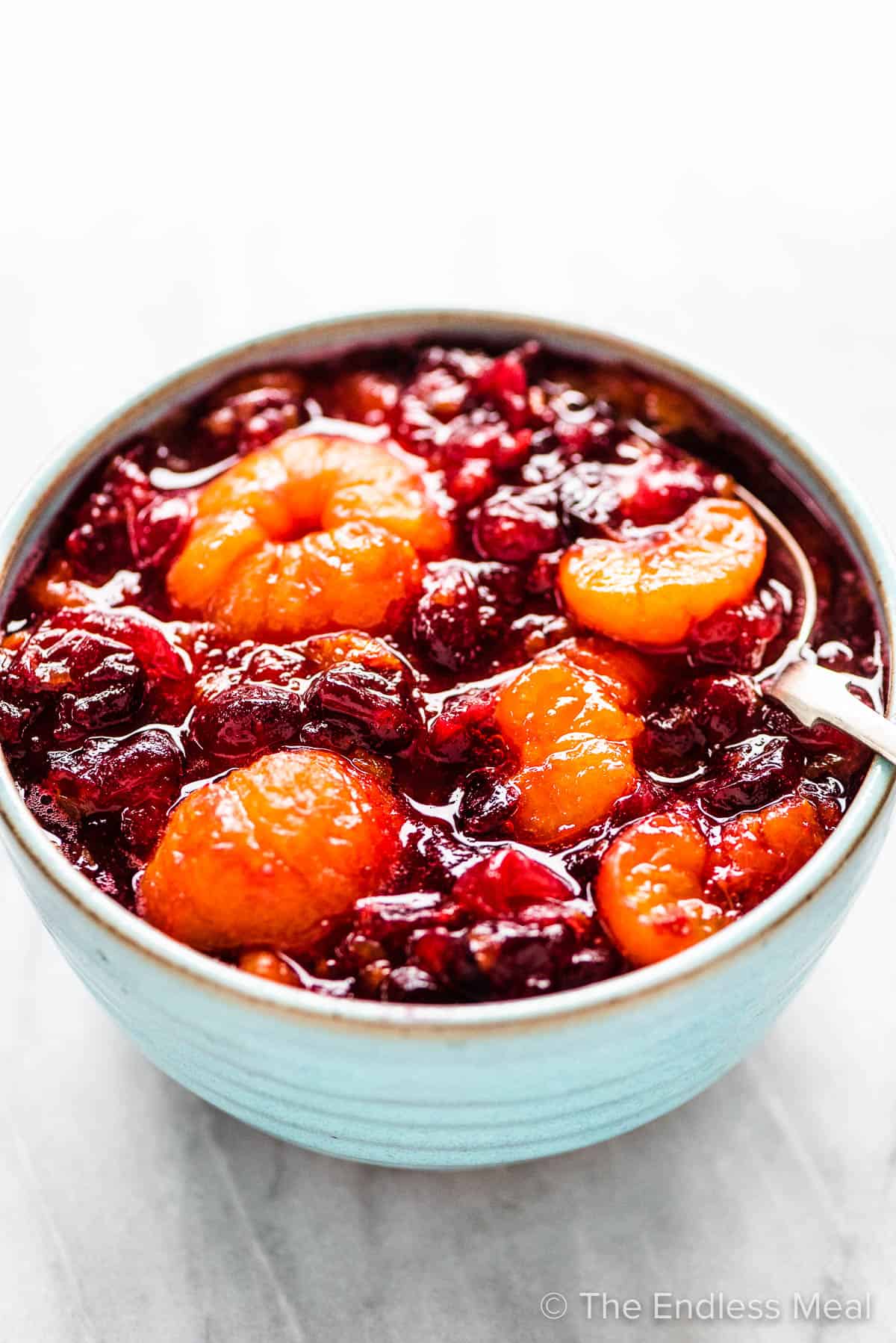 Cranberry sauce with whole mini mandarin oranges in a blue bowl. 