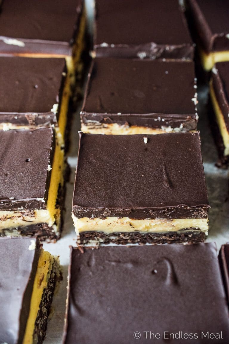 Nanaimo Bars are a classic Canadian Christmas dessert. The holidays wouldn't be the same without them. This is my mom's recipe and it is less sweet than most. That's a good thing! They are made with a chocolate graham cracker, coconut, and walnut crust then topped with a layer of buttery custard and chocolate. They're amazing! | theendlessmeal.com | #nanaimobars #christmasbaking #christmastreats #christmasrecipes #holidaybaking 