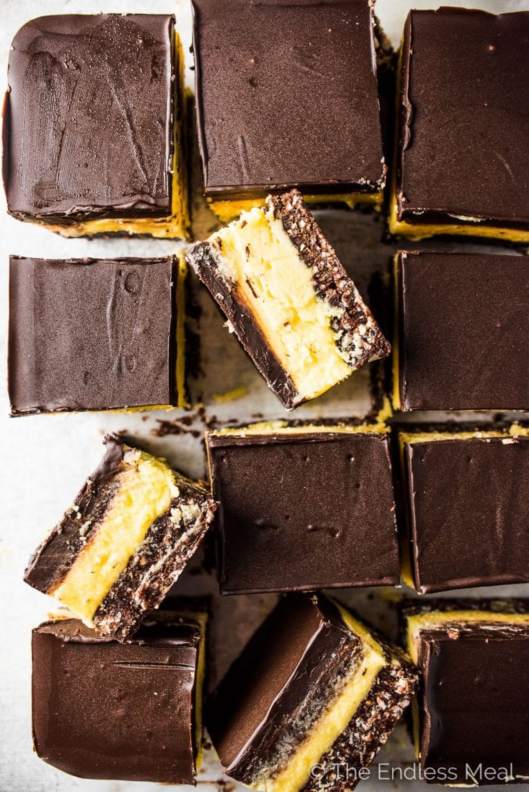 Nanaimo Bars are a classic Canadian Christmas dessert. The holidays wouldn't be the same without them. This is my mom's recipe and it is less sweet than most. That's a good thing! They are made with a chocolate graham cracker, coconut, and walnut crust then topped with a layer of buttery custard and chocolate. They're amazing! | theendlessmeal.com | #nanaimobars #christmasbaking #christmastreats #christmasrecipes #holidaybaking 