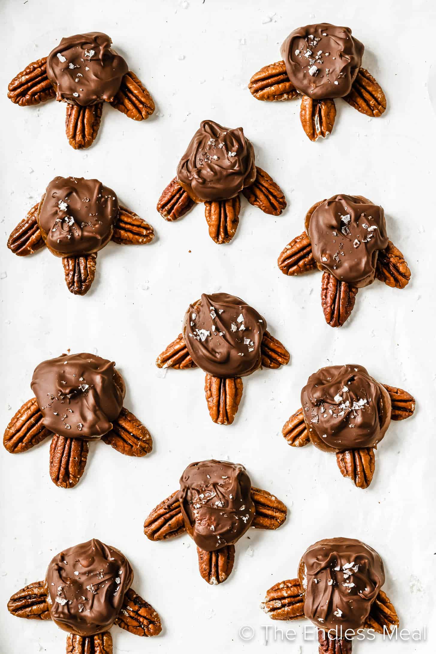 Homemade Chocolate Turtles lined up on parchment paper