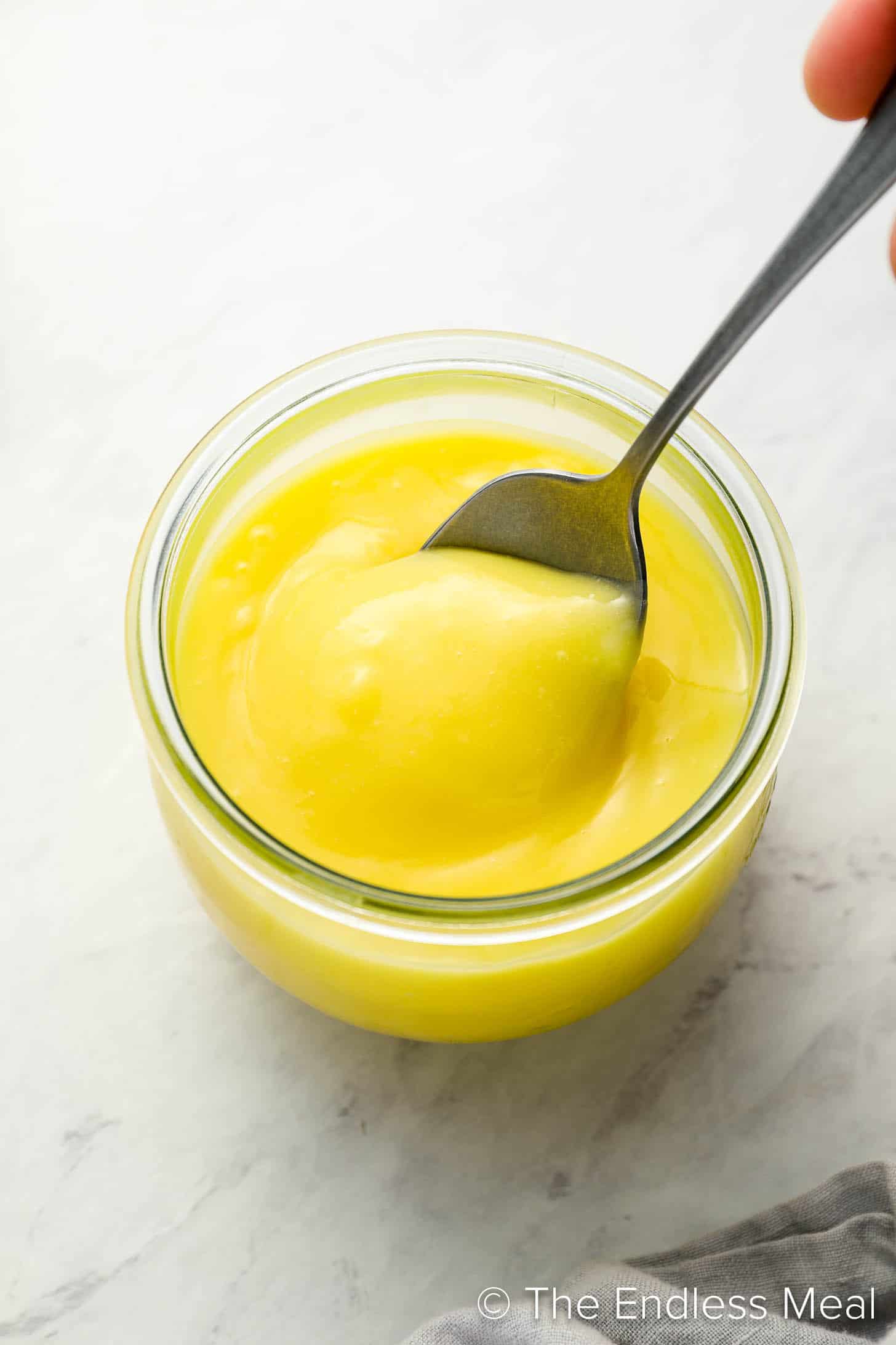 A jar of Lemon Curd with a spoon in it.