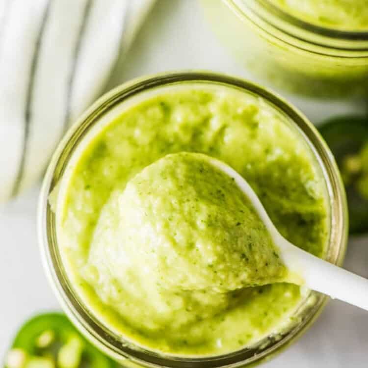 Looking down on a jar of avocado sauce with a spoon in it.