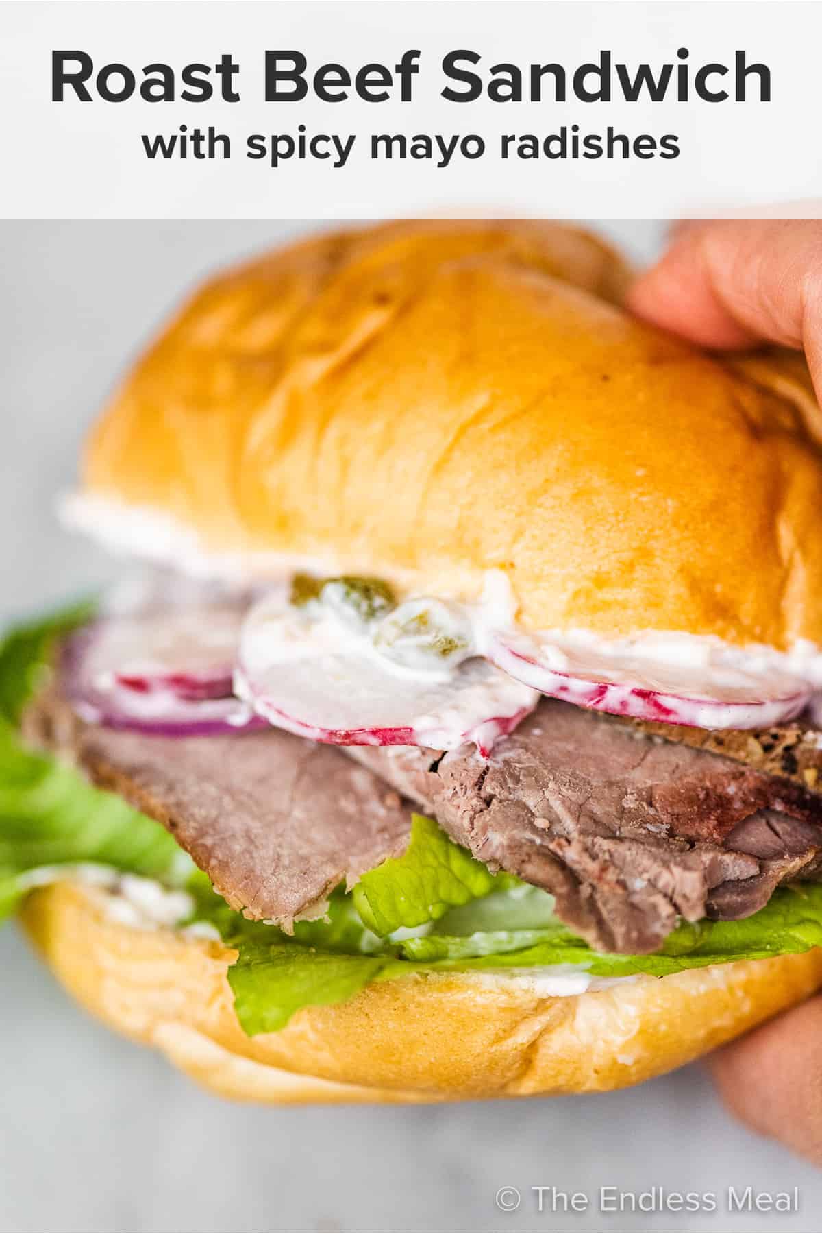 A hand holding a roast beef sandwich with the recipe title on top of the picture.
