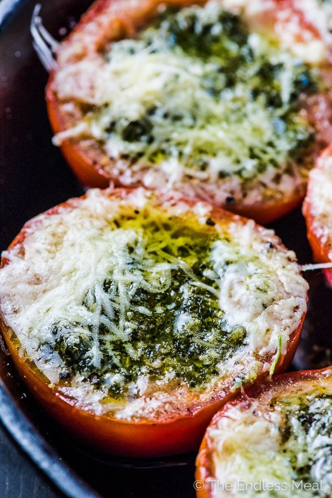 Pesto Stuffed Roasted Tomatoes are a must make side dish/ appetizer. The hollowed out tomato halves are stuffed with an easy to make, garlicky pesto then roasted until the cheese melts and the tomatoes are soft. They're delicious! | vegetarian + gluten-free + keto | #theendlessmeal #tomatoes #pesto #stuffedtomatoes #keto #glutenfree #vegetarian 