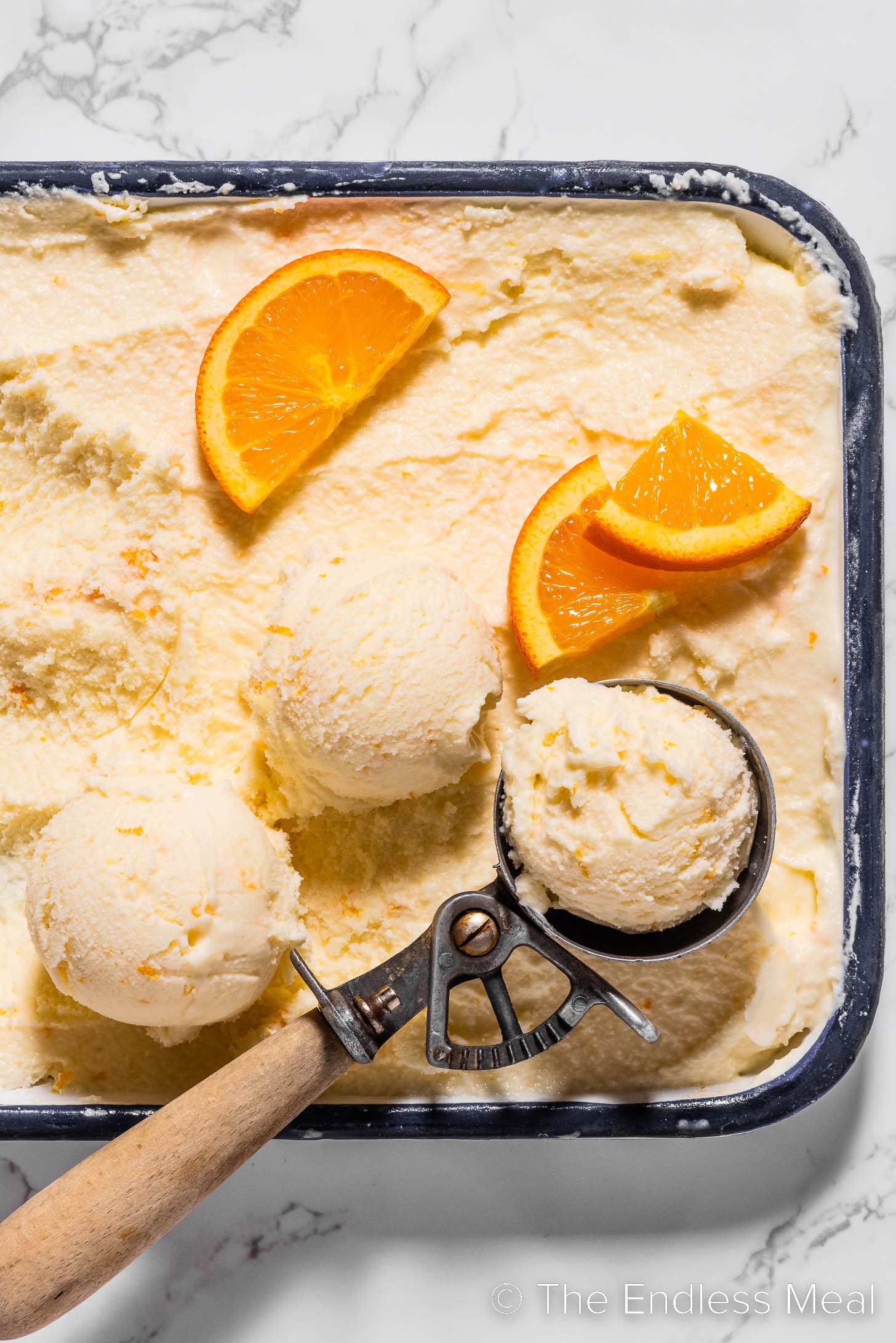 an ice cream scoop serving orange sherbet.