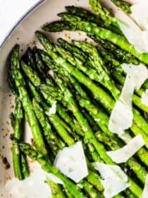 A pan of sauteed asparagus with garlic and shaved parmesan.