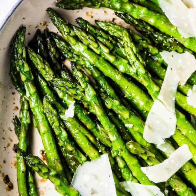 A pan of sauteed asparagus with garlic and shaved parmesan.