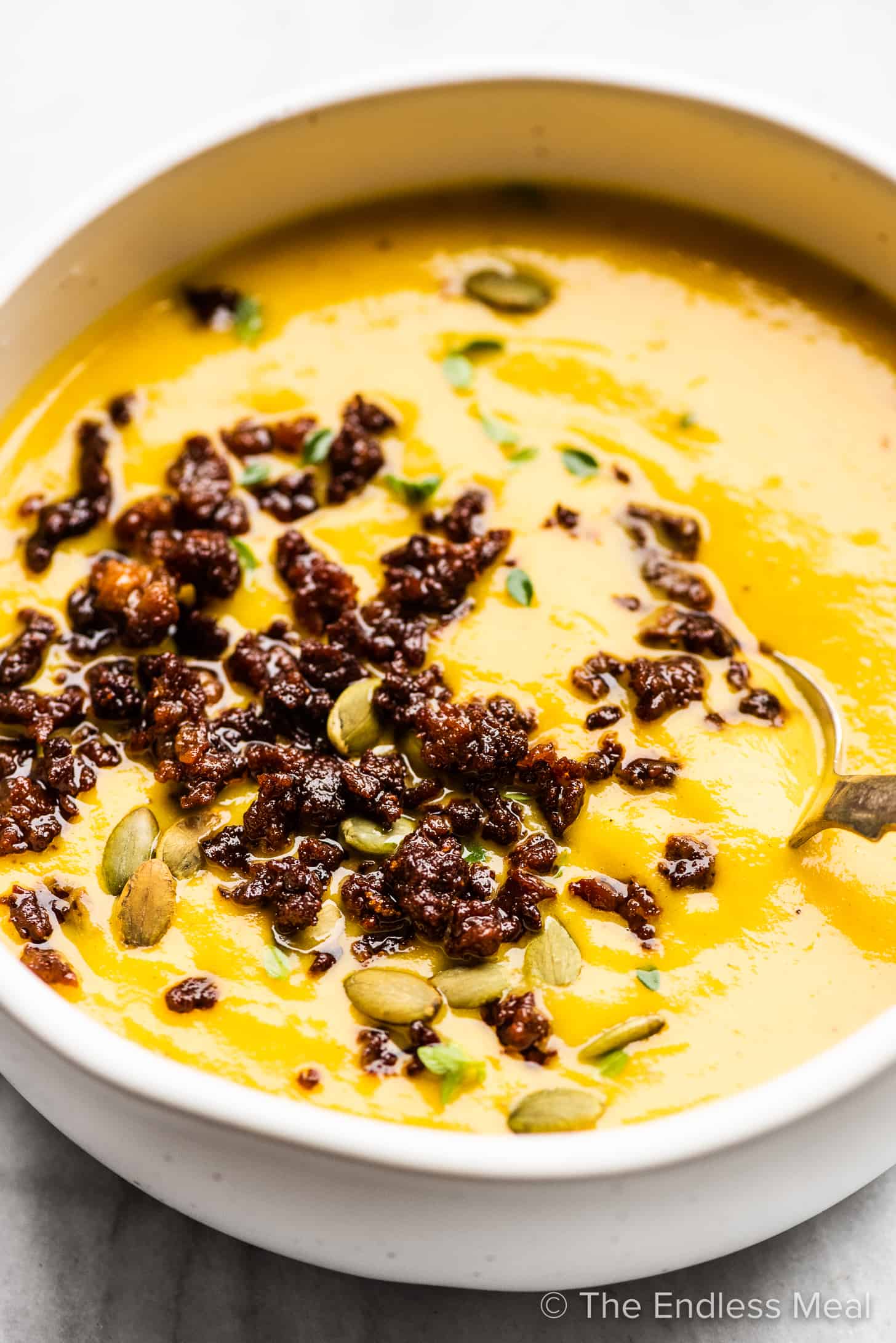 A close up of roasted butternut squash soup with crispy chorizo.