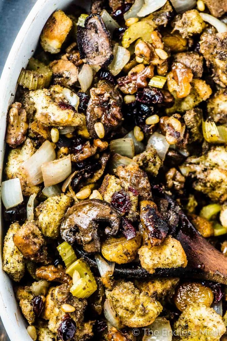 The Best Stuffing Recipe Ever in a casserole dish with a wooden spoon taking out a spoonful. 