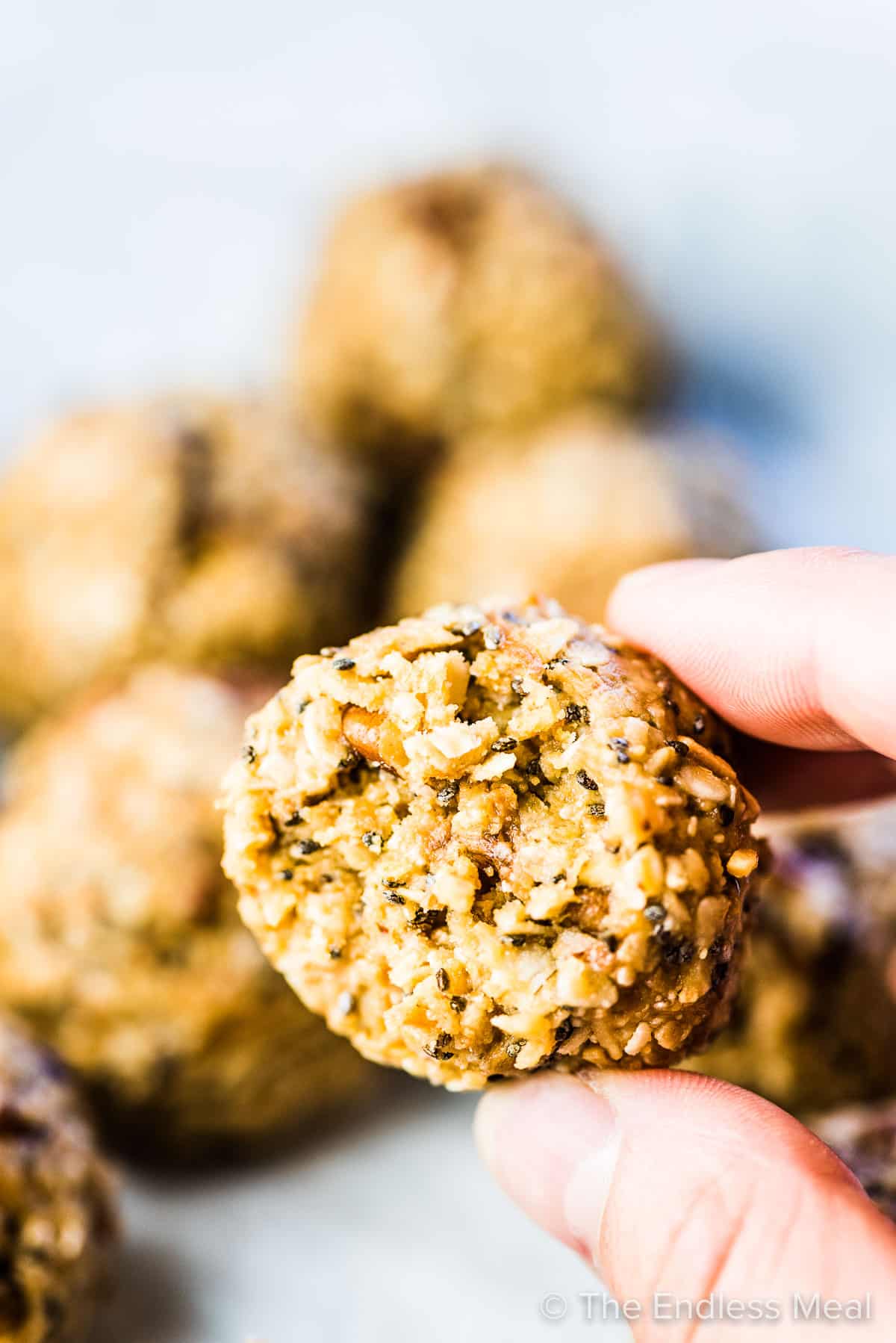 A hand holding a no bake energy ball with a bite taken out of it. 