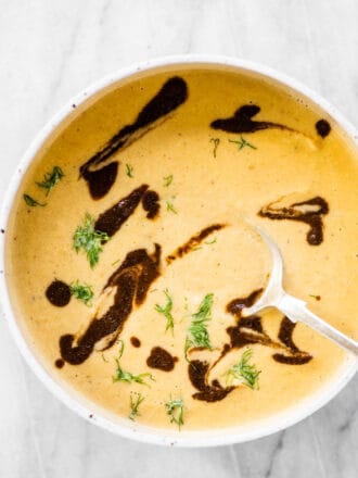 A bowl of roasted fennel black garlic soup with some black garlic drizzle on the top.