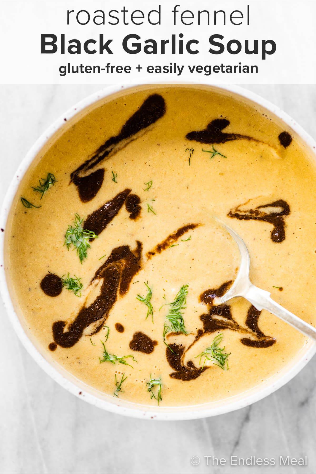 A bowl of roasted fennel black garlic soup with some black garlic drizzle and the recipe title on top of the picture.