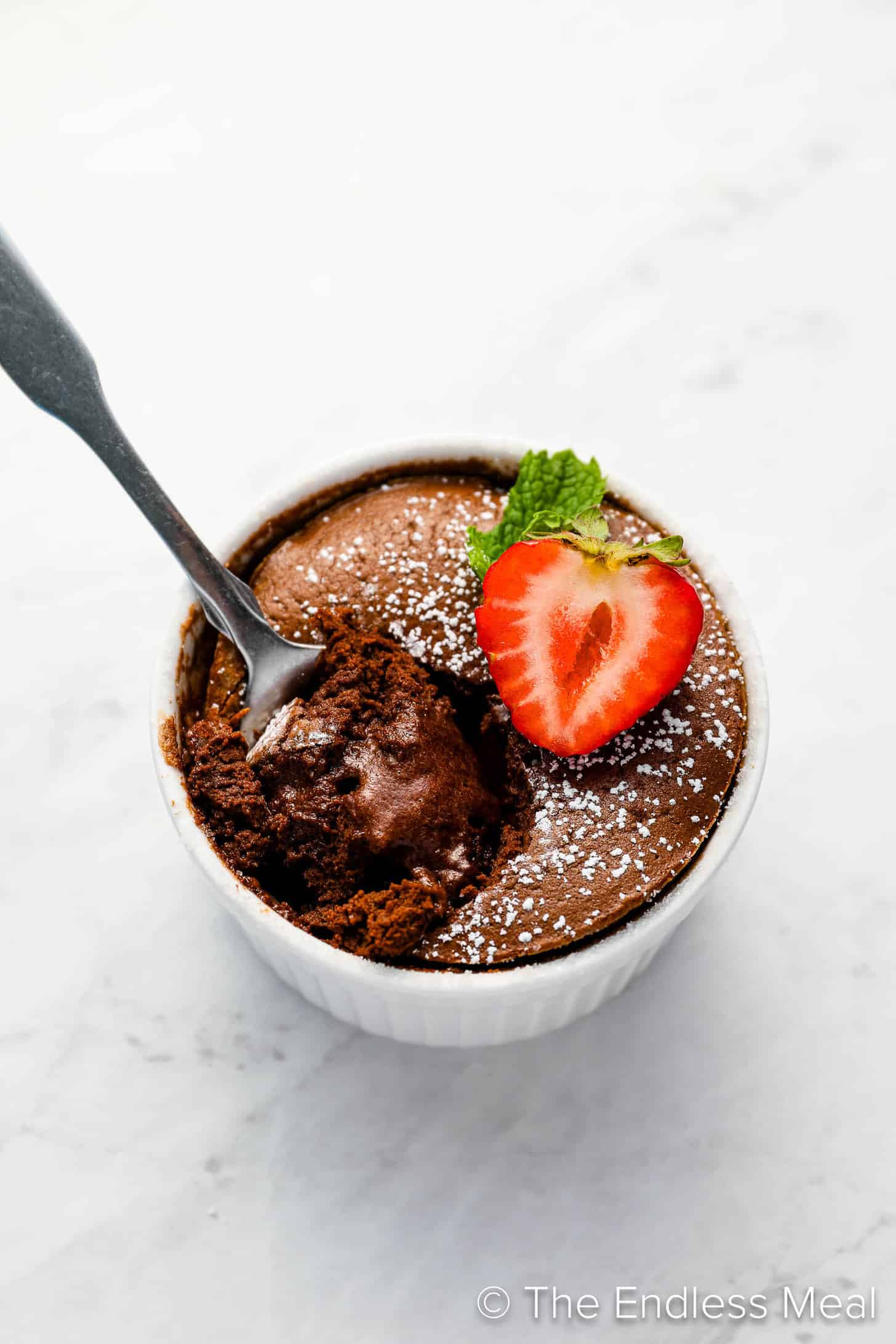 Chocolate Soufflé in a white ramekin topped with a strawberry