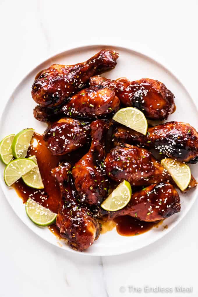 honey sriracha chicken on a plate with lime wedges.