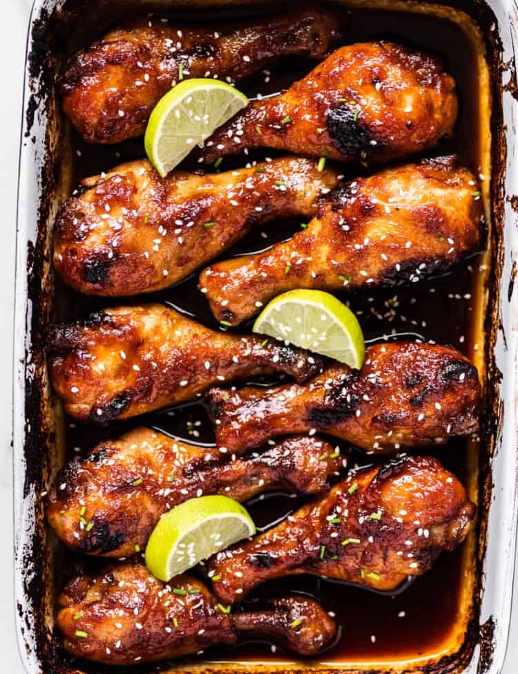 honey sriracha chicken in a baking pan with lots of spicy sweet and sour sauce.