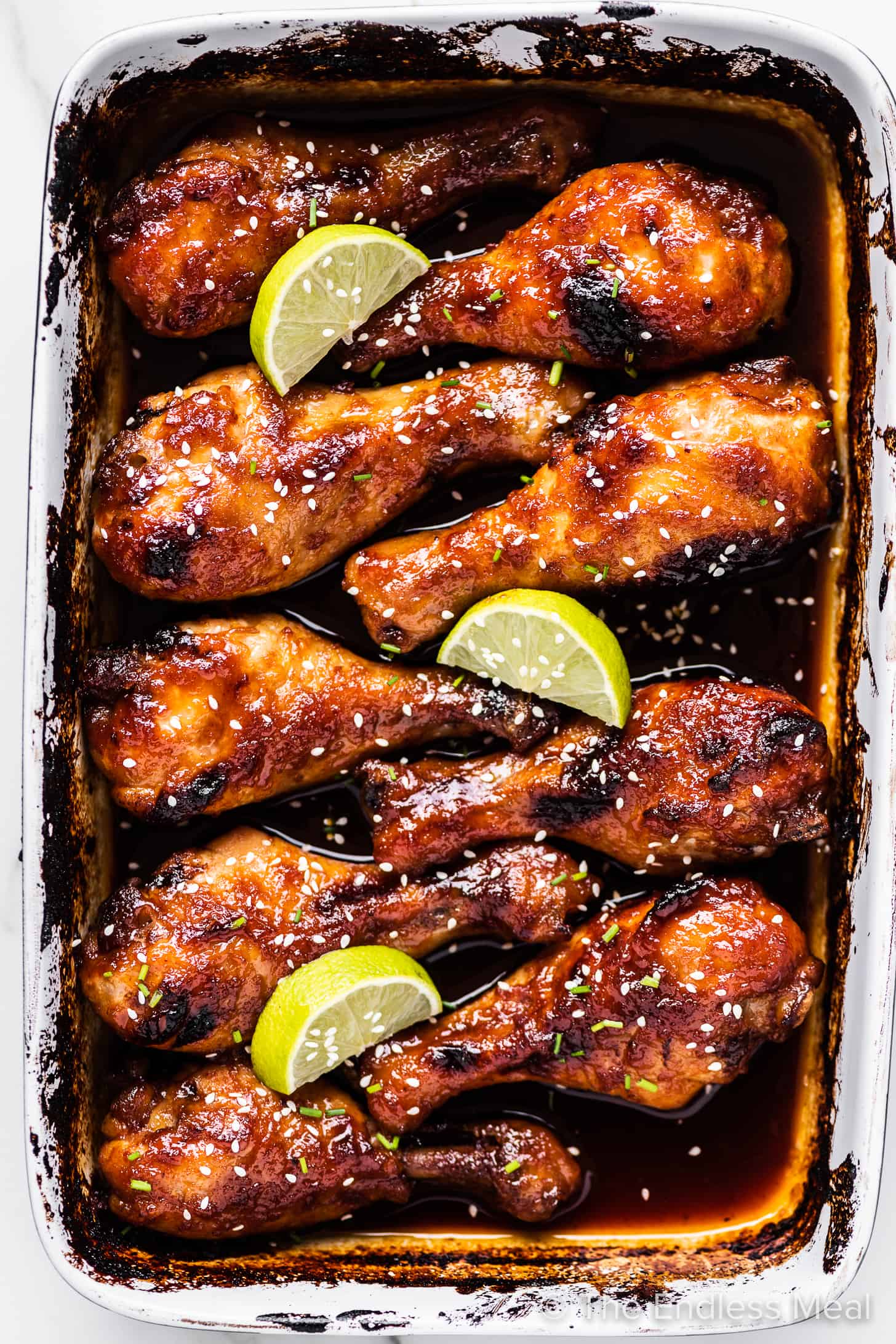 honey sriracha chicken in a baking pan with lots of spicy sweet and sour sauce. 
