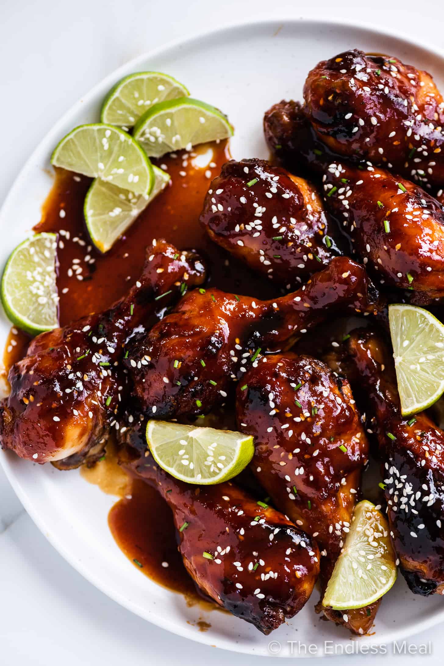 a close up of honey sriracha chicken on a plate with lime wedges.