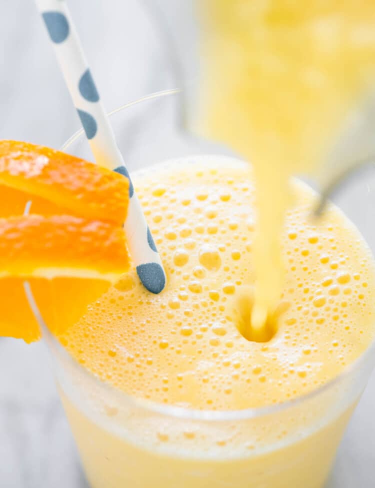 An orange creamsicle smoothie being poured into a cup.