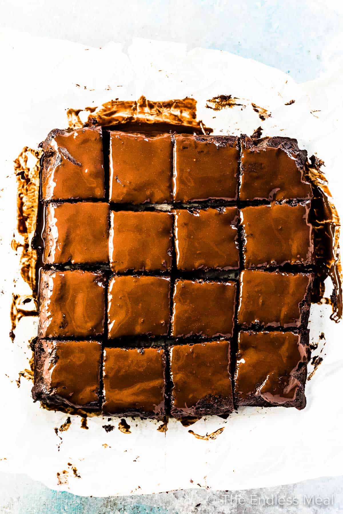 Looking down on 16 squares of chocolate zucchini brownies covered in chocolate glaze.
