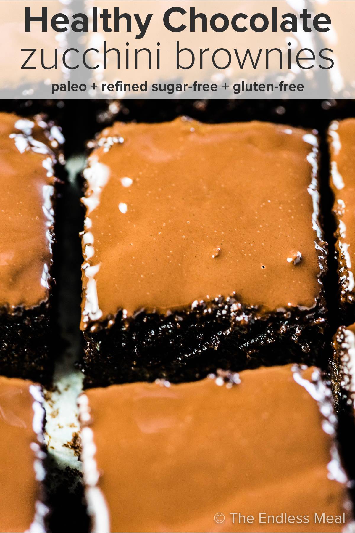 Squares of chocolate zucchini brownies drippy chocolate glaze and the recipe title at the top of the picture. 