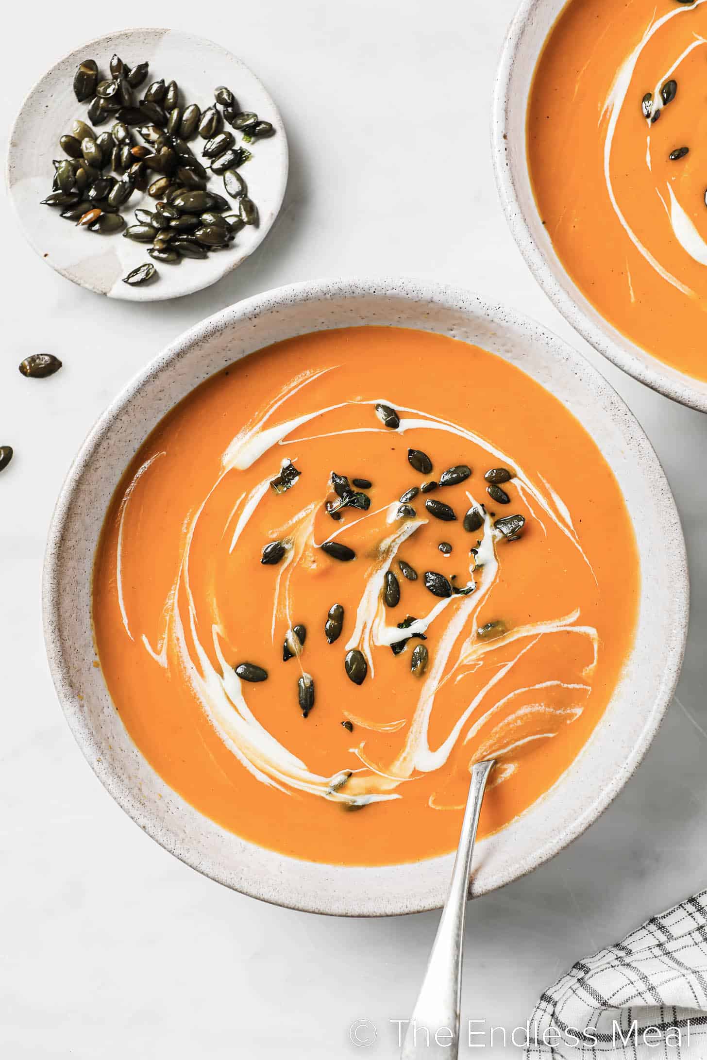 A bowl of Spicy Butternut Squash Soup with a spoon in it.