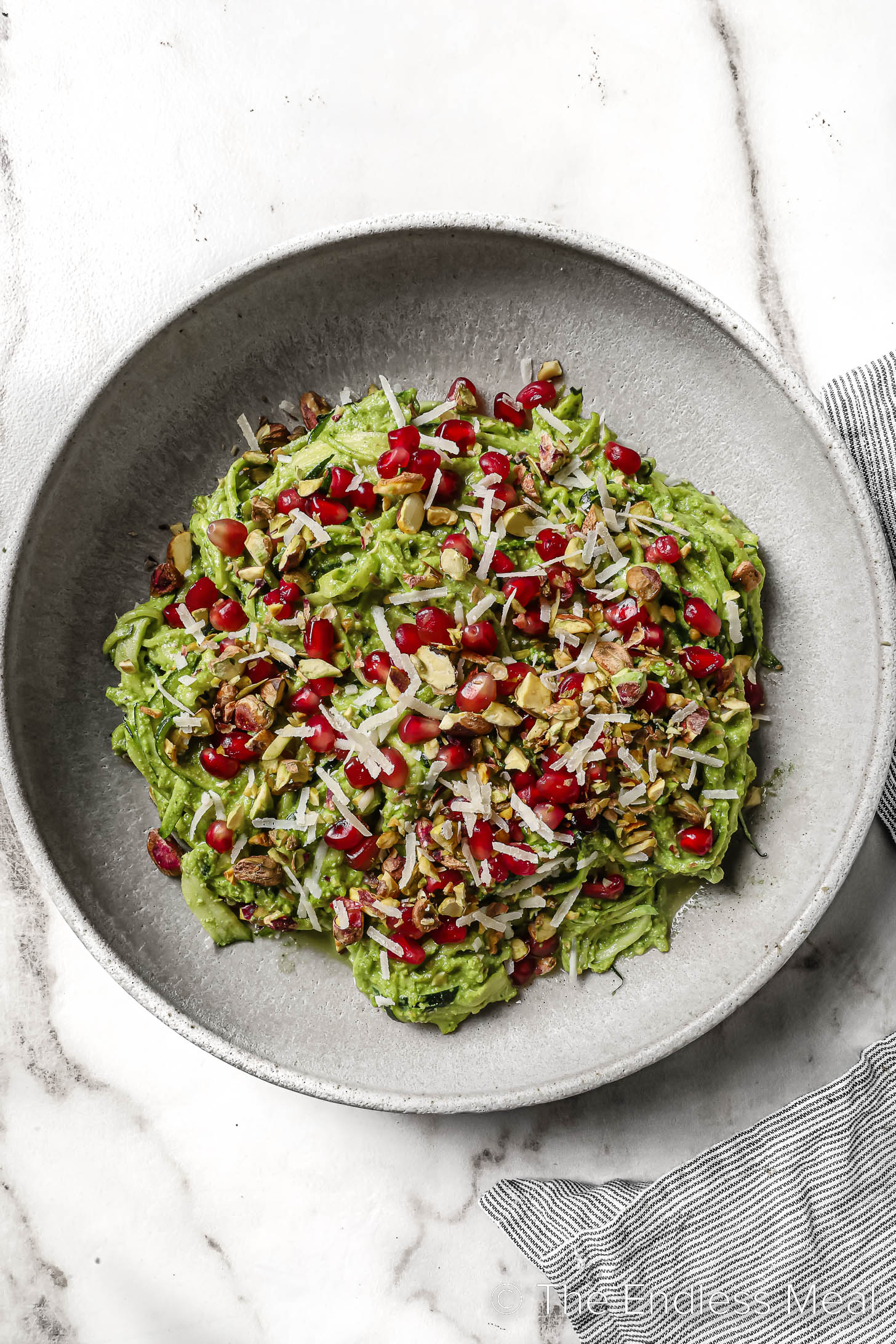 Zucchini noodles with pesto in a bowl with pomegranate and pistachios