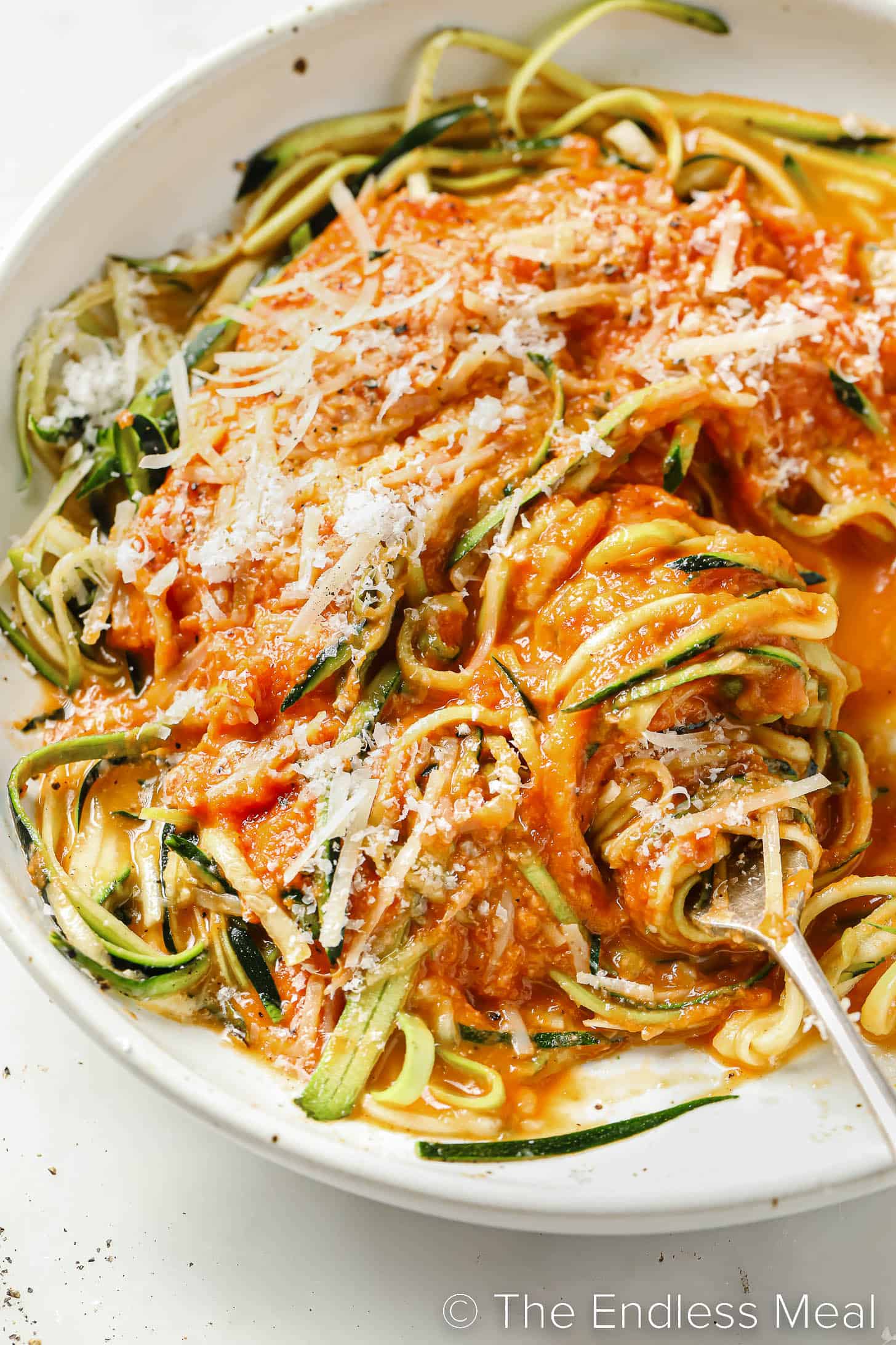 a fork twirling zucchini spaghetti in a bowl