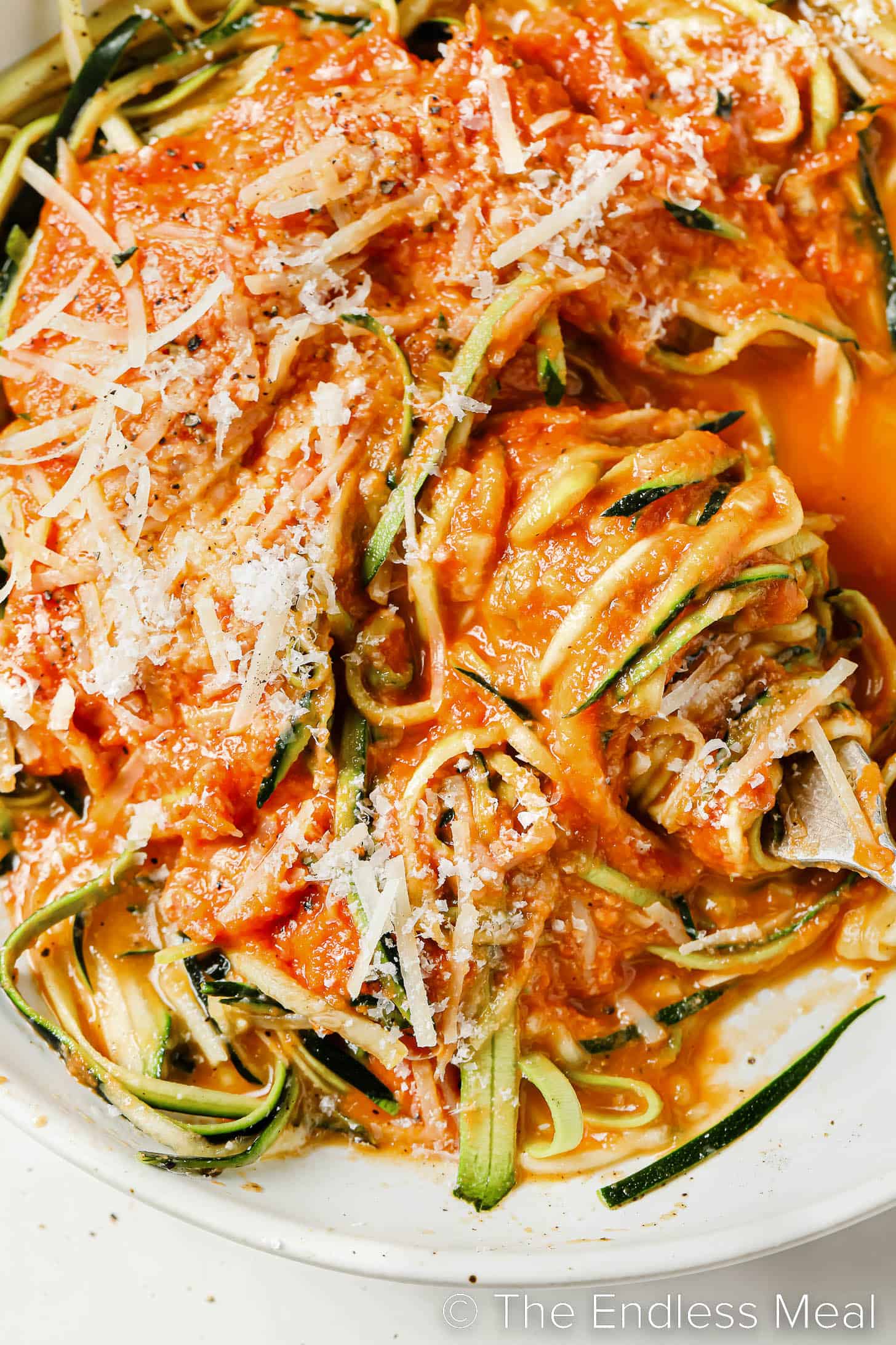 a close up of a bowl of zucchini spaghetti with tomato sauce.
