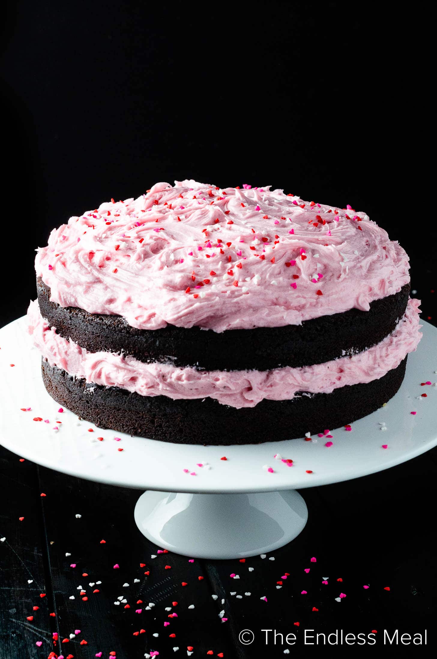 A Chocolate Beet Cake on a cake stand with pink frosting