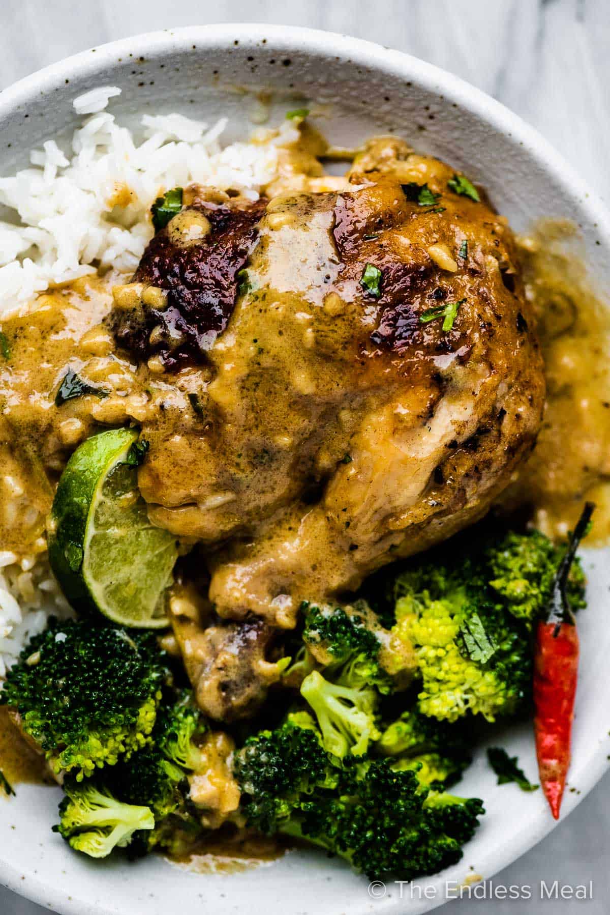 Coconut milk chicken on a plate with rice and broccoli.