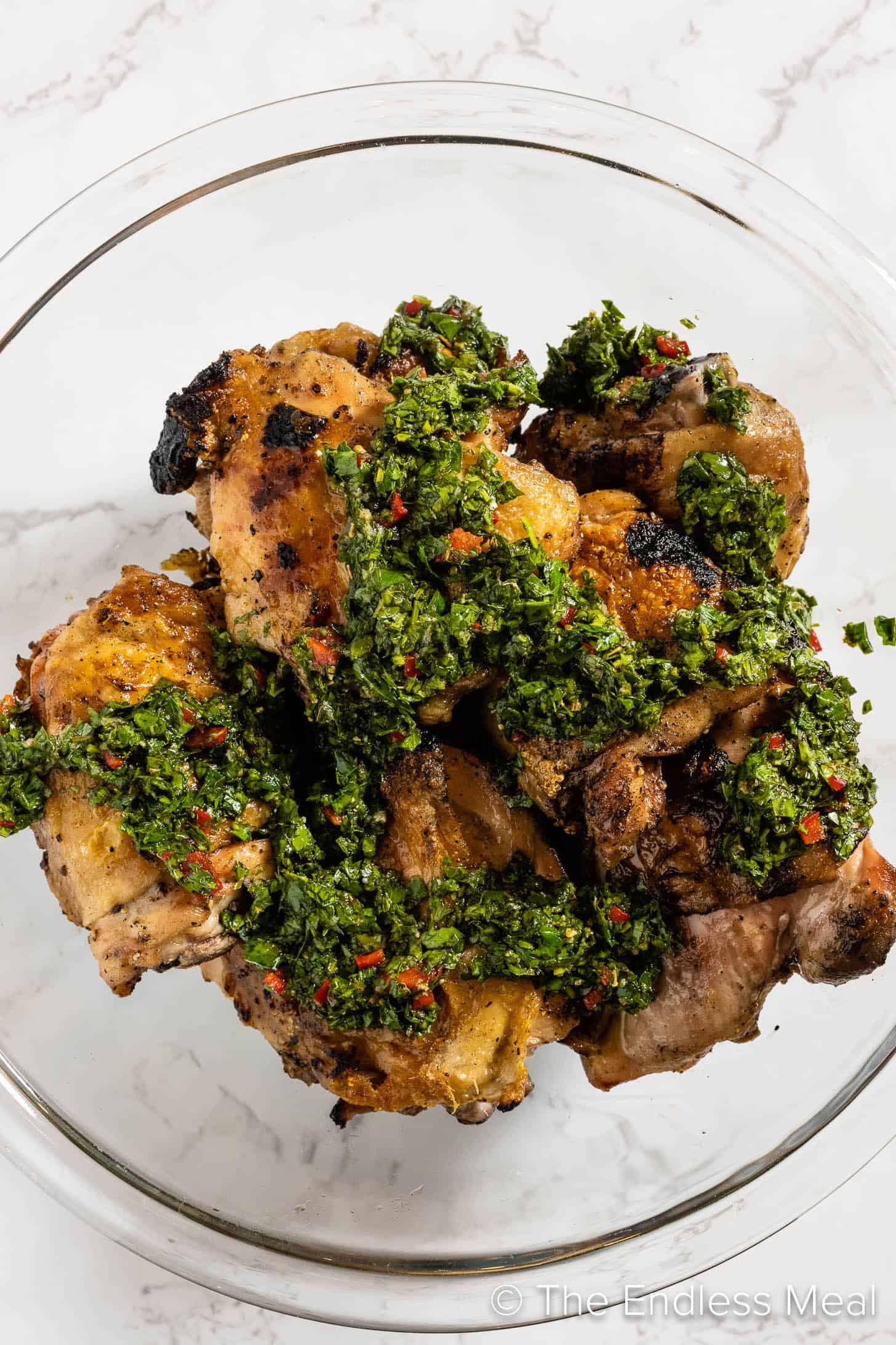 Mixing Chimichurri Chicken in a glass bowl