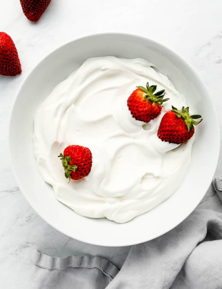 A bowl of Coconut Whipped Cream with strawberries on top