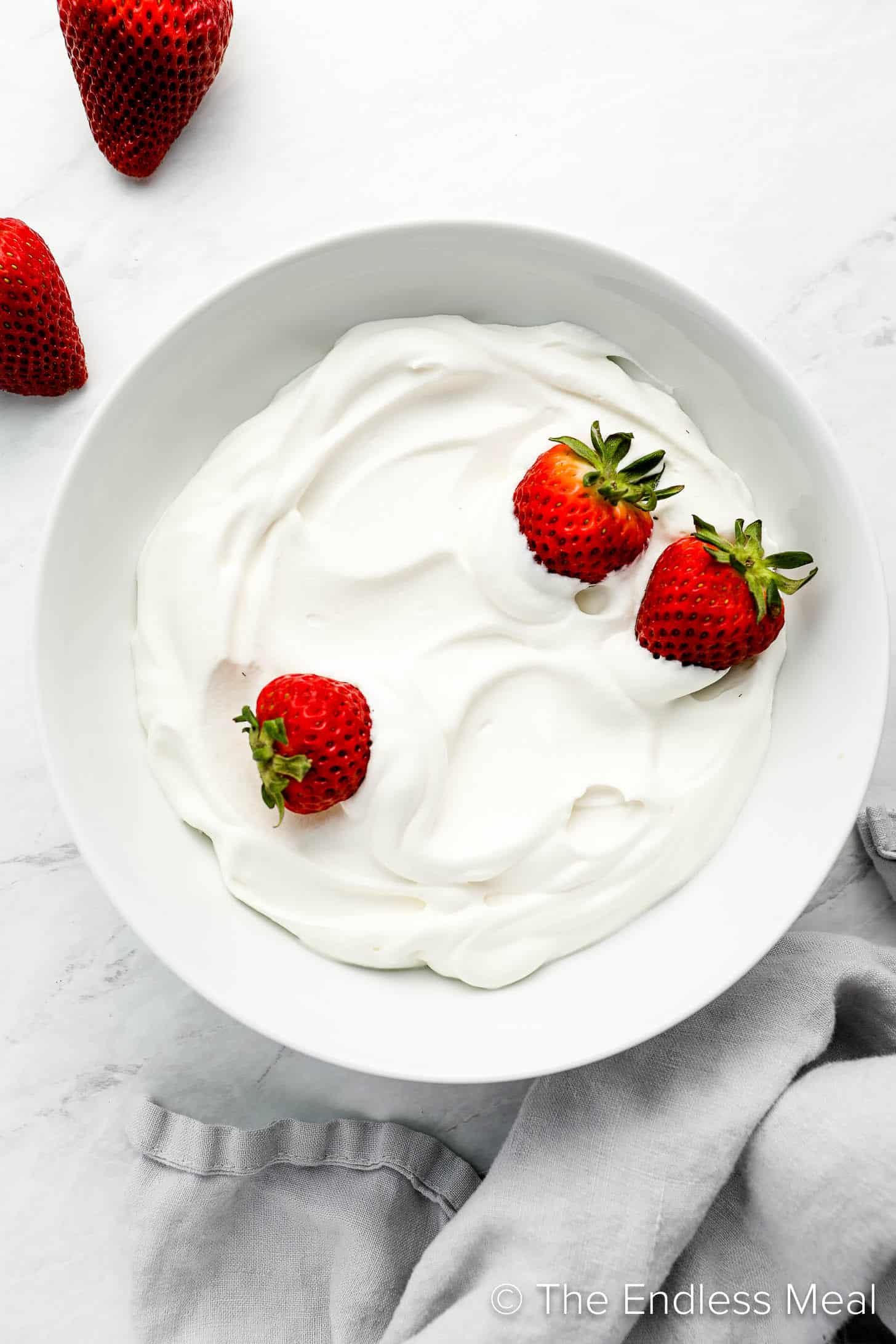 A bowl of Coconut Whipped Cream with strawberries on top