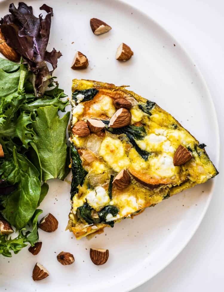a slice of Sweet Potato Frittata on a plate with a salad