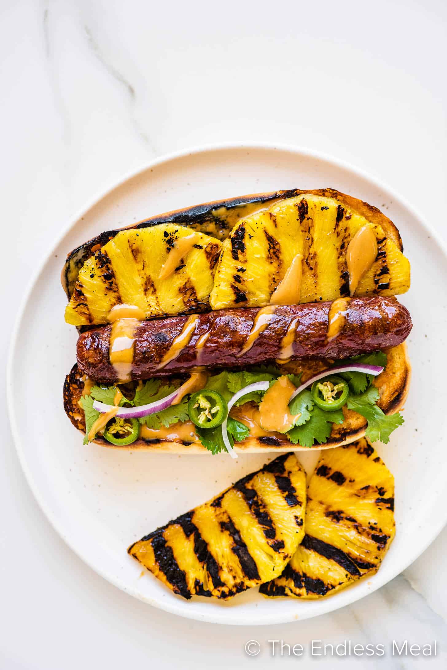 Hawaiian Hot Dogs on a plate with a side of grilled pineapple
