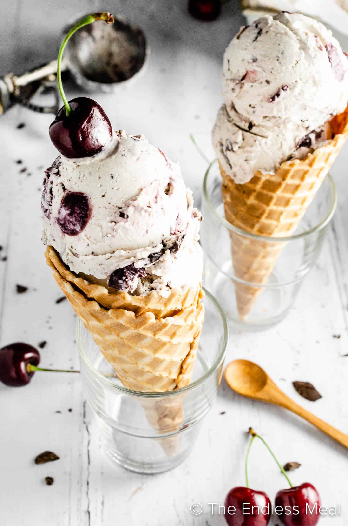Two Vegan Cherry Garcia ice cream cones topped with a cherry