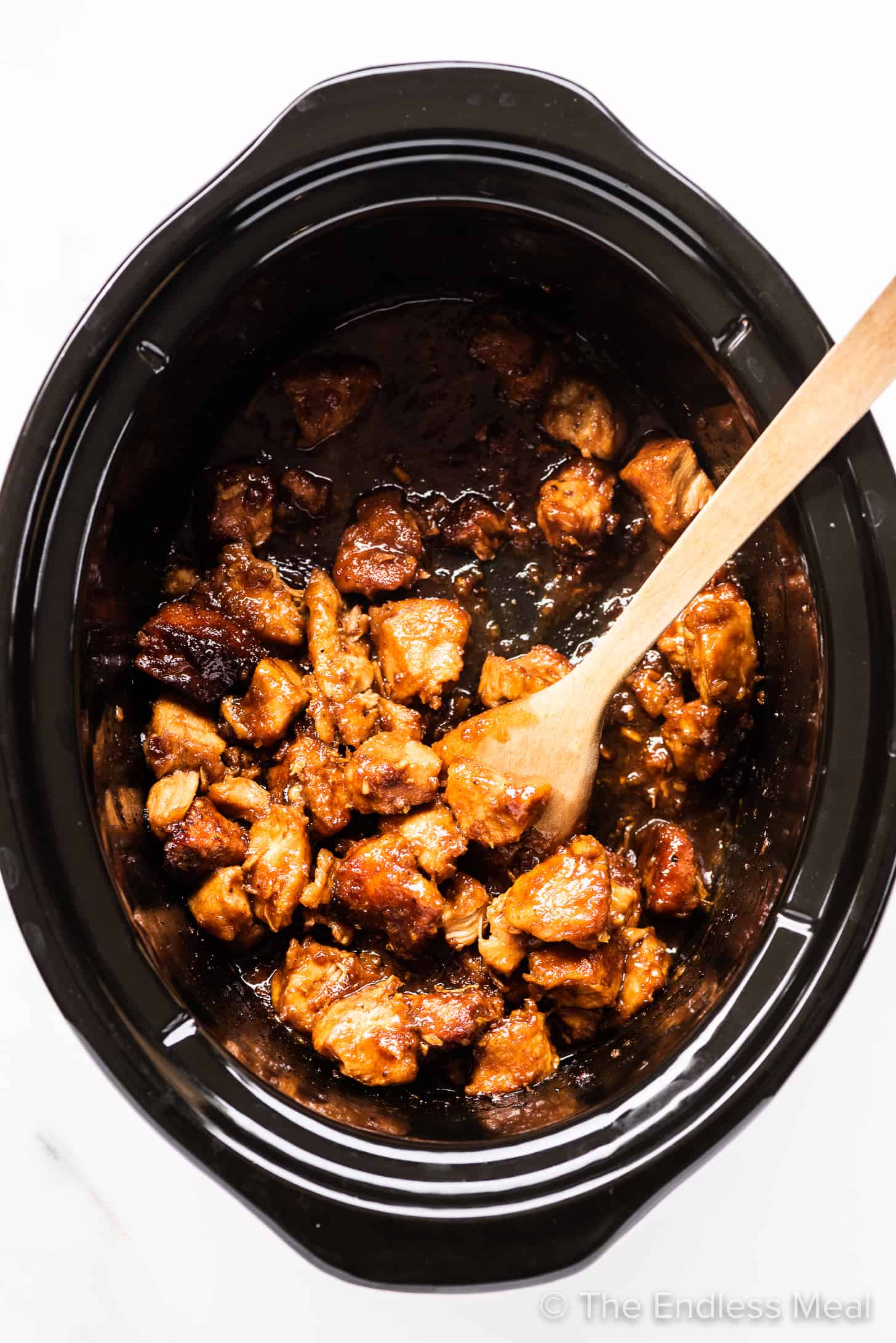 General Tso's Chicken in a crockpot with a wooden spoon