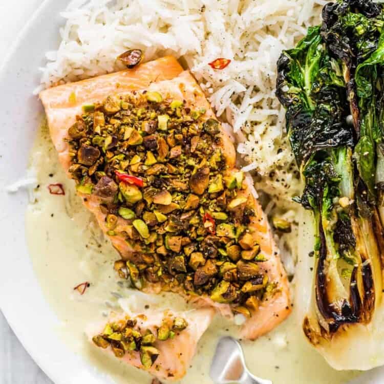 Pistachio crusted salmon on a plate with rice and bok choy.