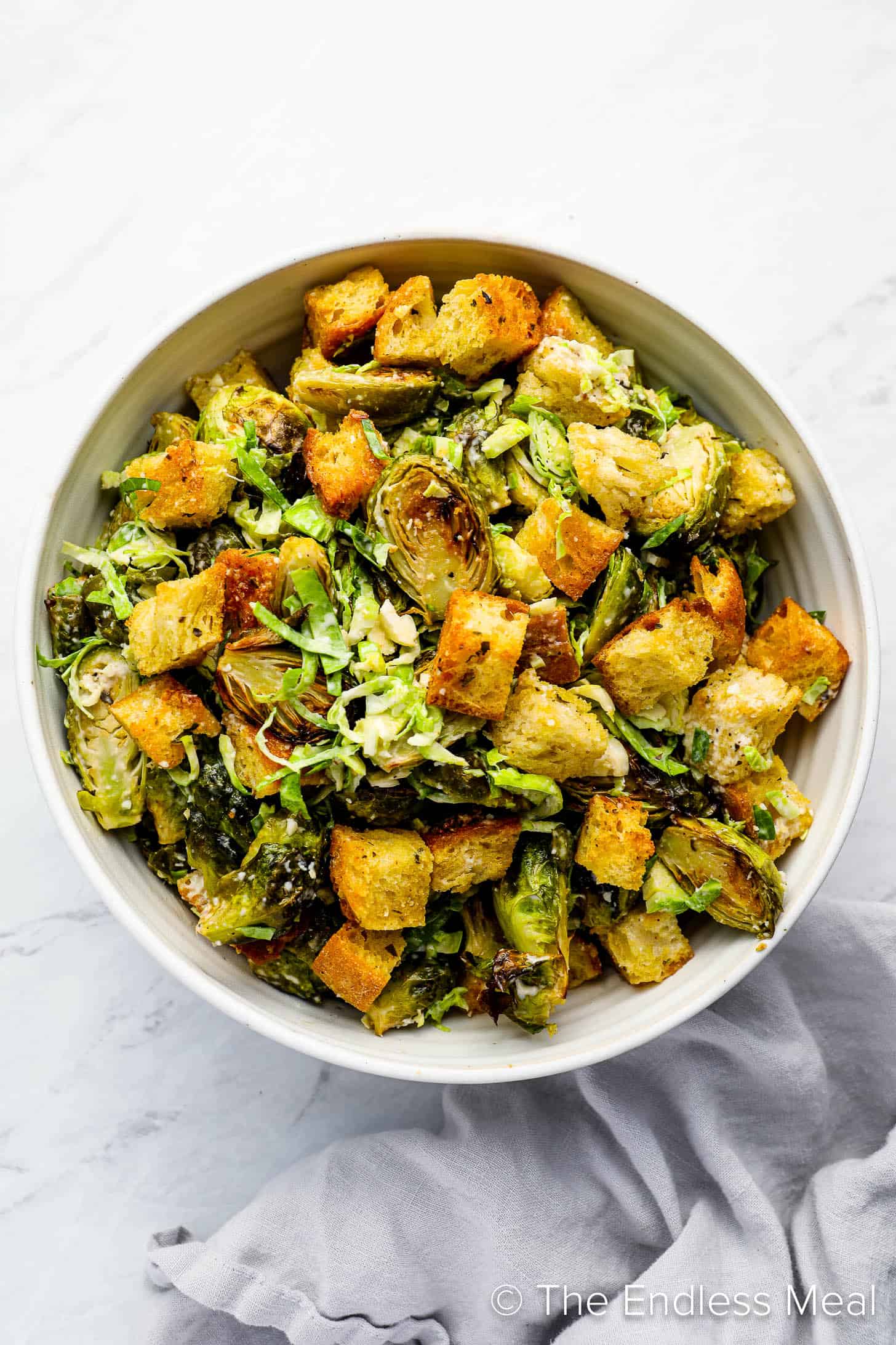 A salad bowl with caesar salad made with brussels sprouts and croutons