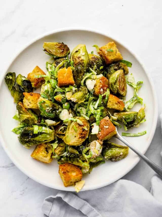 Brussels Sprouts Caesar Salad on a white plate with a fork