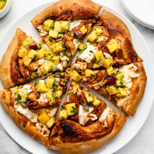 A sliced Leftover Turkey Pizza with pineapple salsa on top.