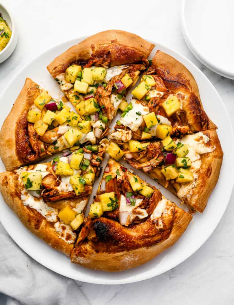 A sliced Leftover Turkey Pizza with pineapple salsa on top.