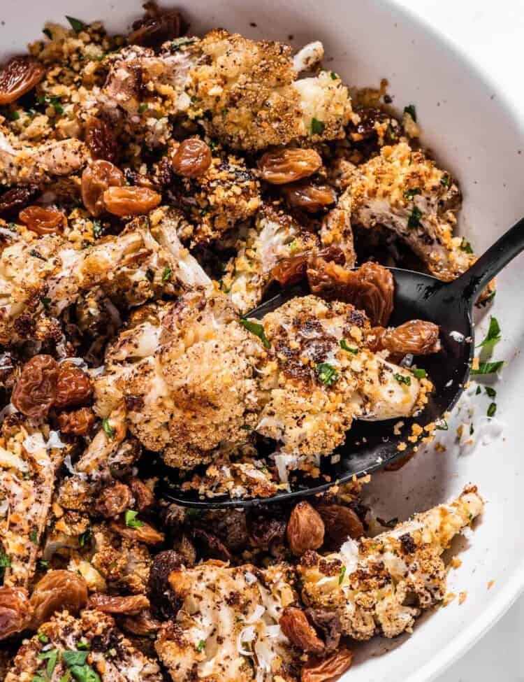 a spoon scooping some crispy Blackened Cauliflower from a serving bowl