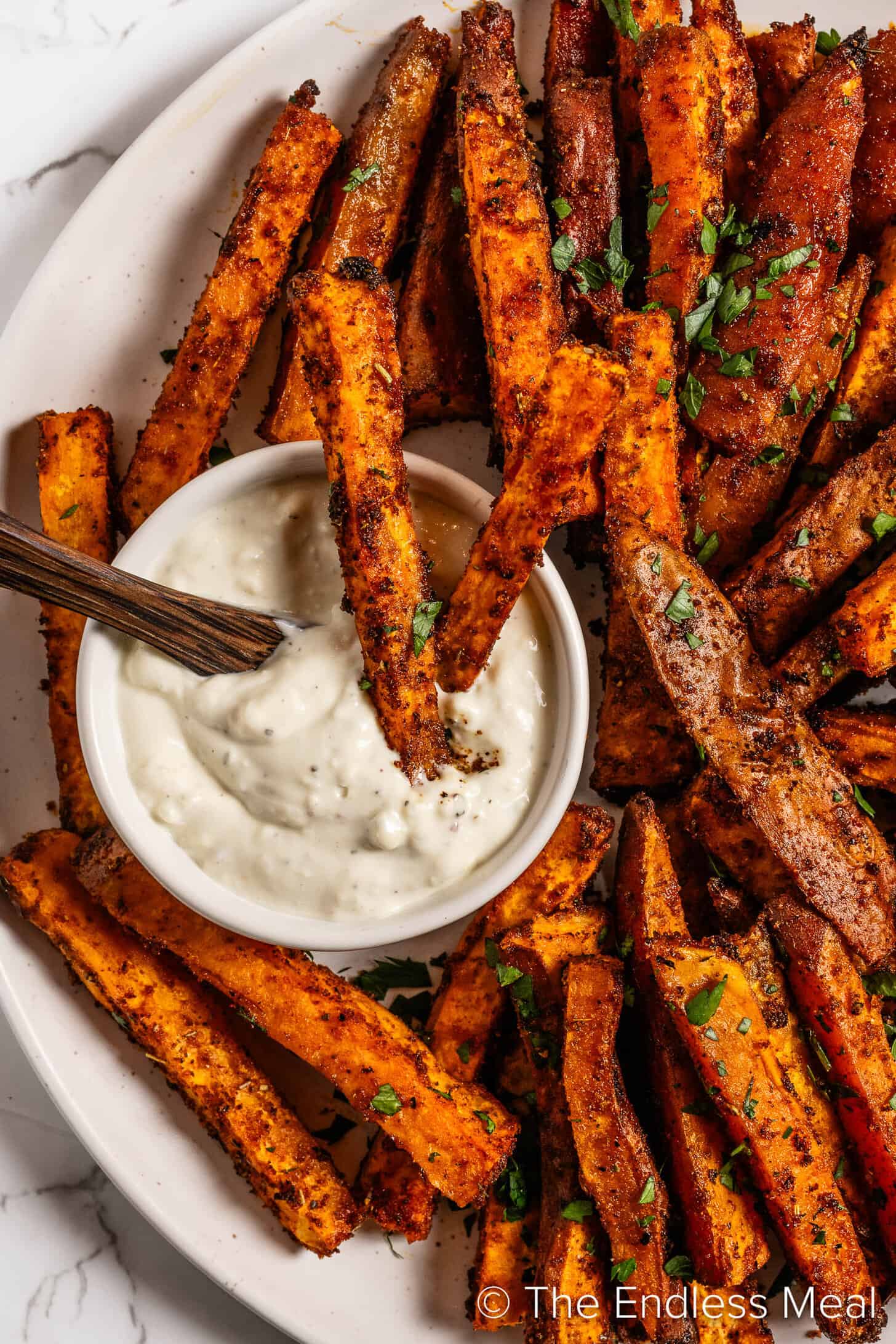 Cajun Sweet Potato Fries being dipped into blue cheese sauce