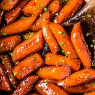 A skillet full honey glazed carrots (candied carrots!) with some minced chives sprinkled over the top.