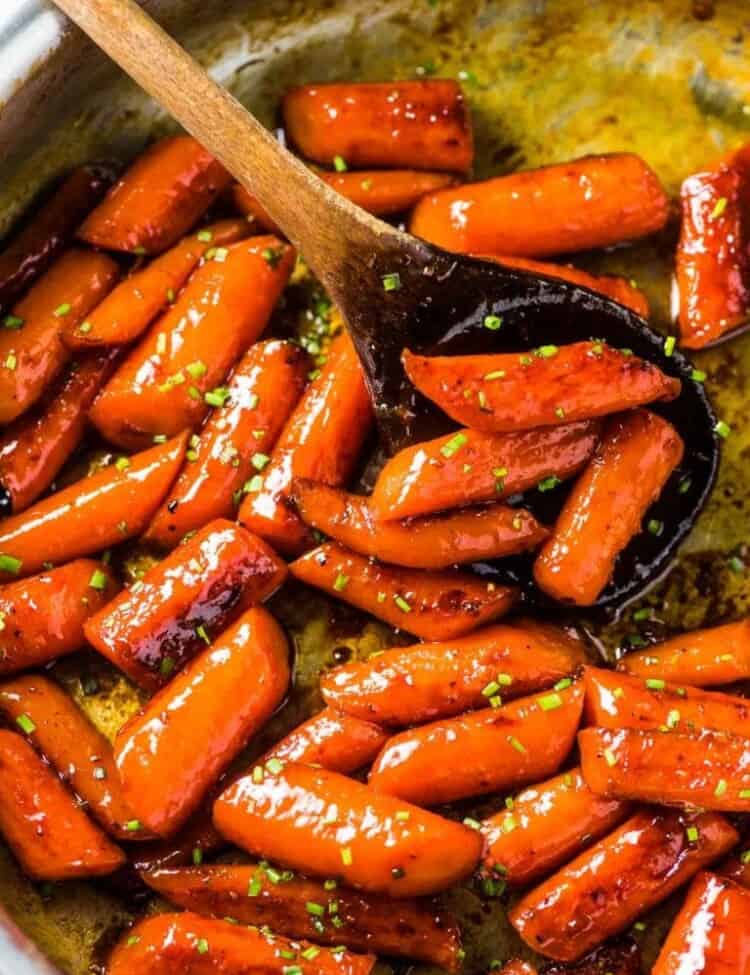 A skillet full of glazed honey roasted carrots (candied carrots!) with some minced chives sprinkled over the top.